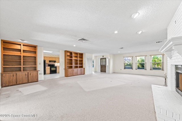 unfurnished living room featuring light carpet, visible vents, a brick fireplace, and a textured ceiling