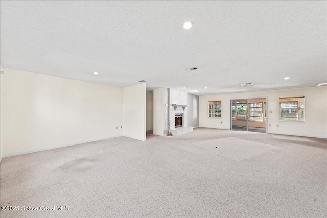 unfurnished living room with a textured ceiling, recessed lighting, a fireplace, baseboards, and light colored carpet