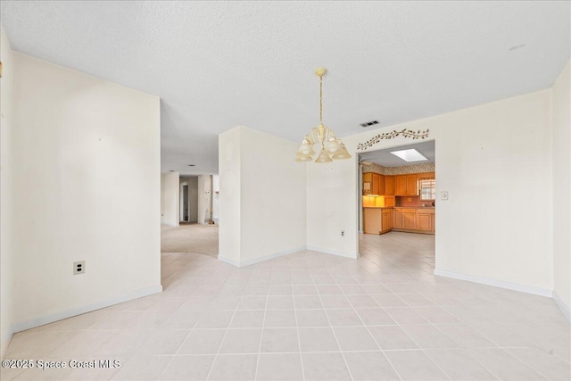 empty room featuring light tile patterned floors, baseboards, visible vents, an inviting chandelier, and a textured ceiling