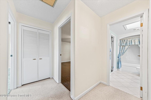 corridor with carpet floors, a textured ceiling, and tile patterned flooring