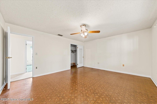 unfurnished bedroom featuring a ceiling fan, baseboards, visible vents, a textured ceiling, and tile patterned floors