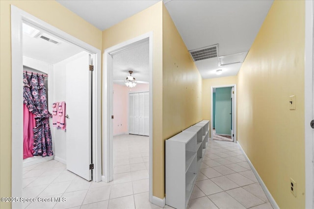 corridor with light tile patterned flooring, visible vents, and baseboards