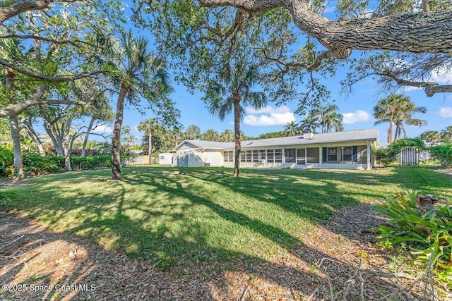 exterior space featuring fence, a lawn, and a sunroom