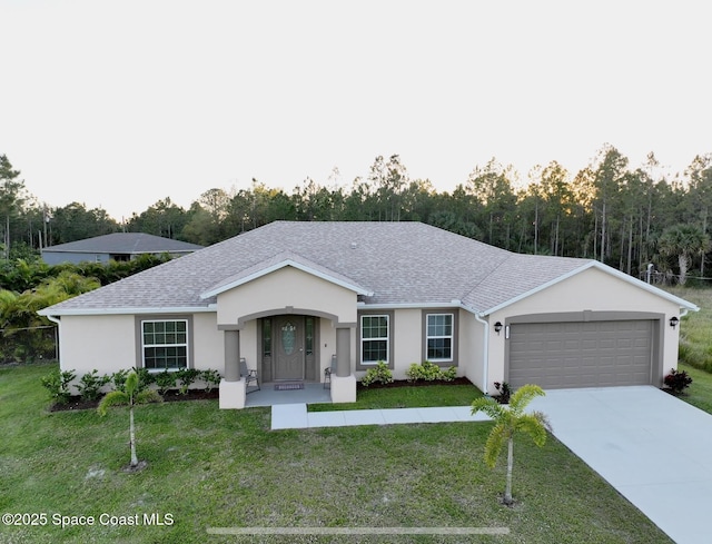 ranch-style home featuring stucco siding, driveway, a shingled roof, an attached garage, and a front yard