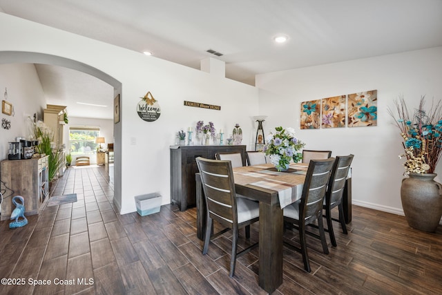 dining room featuring dark wood-style floors, visible vents, baseboards, recessed lighting, and arched walkways