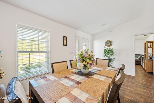 dining room with vaulted ceiling, wood finished floors, and baseboards