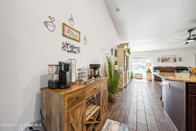 kitchen with wood finish floors, light stone counters, open floor plan, and ceiling fan