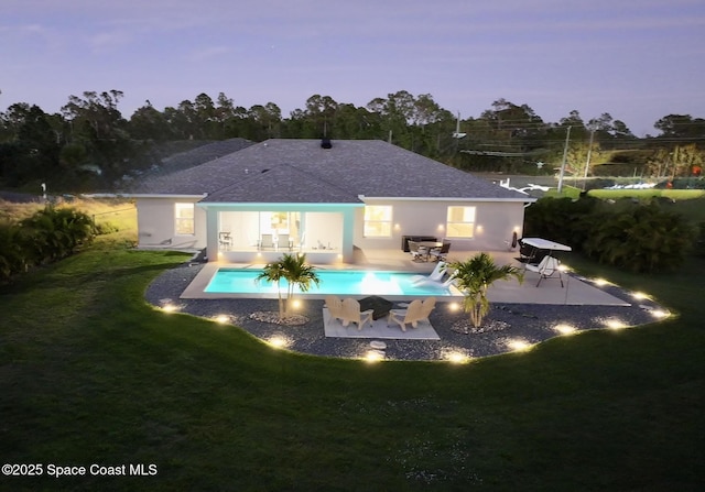 rear view of property with a patio, a yard, an outdoor pool, and stucco siding