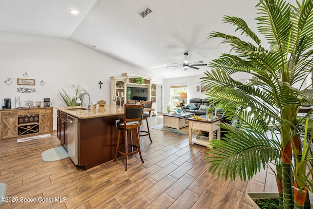 kitchen featuring a ceiling fan, wood finished floors, visible vents, a sink, and dishwasher