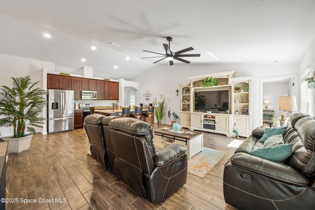 living area with wood finish floors, lofted ceiling, arched walkways, ceiling fan, and a textured ceiling