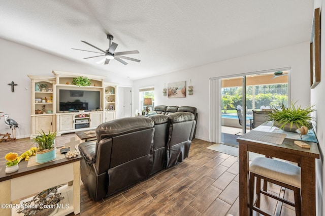 living room with ceiling fan, a textured ceiling, and wood tiled floor