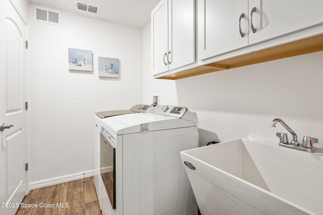 washroom with independent washer and dryer, cabinet space, visible vents, and a sink