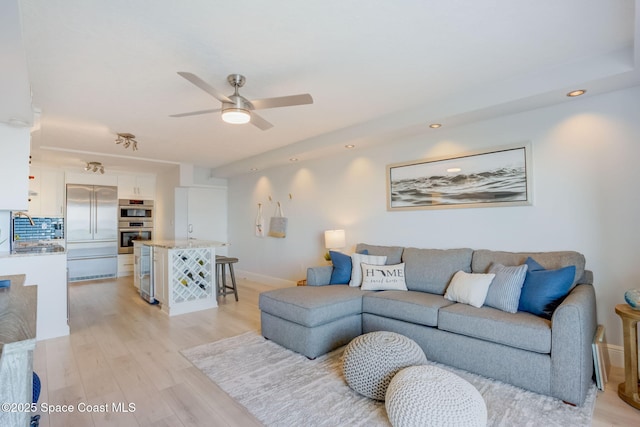 living room featuring a ceiling fan, recessed lighting, light wood-style floors, and baseboards