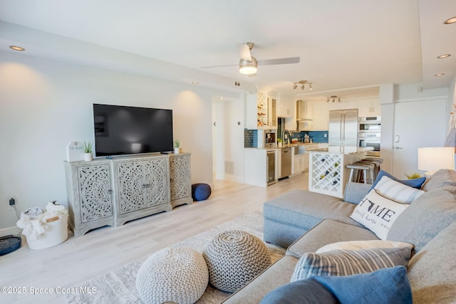 living area with light wood finished floors, visible vents, recessed lighting, and a ceiling fan