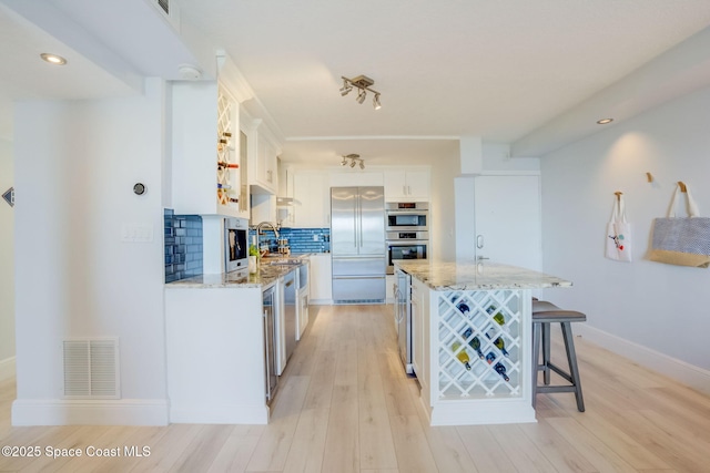 kitchen featuring visible vents, backsplash, light stone counters, appliances with stainless steel finishes, and white cabinets