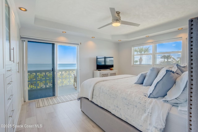 bedroom featuring a tray ceiling, recessed lighting, access to exterior, and light wood finished floors