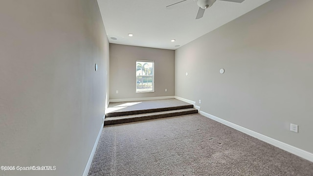 carpeted empty room featuring a ceiling fan and baseboards