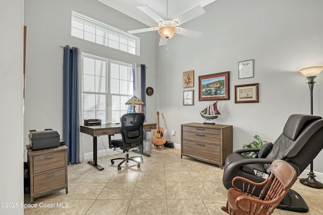 office with light tile patterned floors, baseboards, a towering ceiling, and a ceiling fan