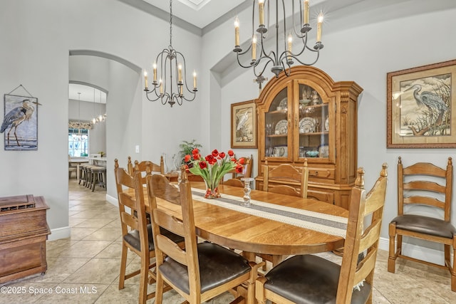 dining room featuring baseboards, arched walkways, an inviting chandelier, and light tile patterned flooring