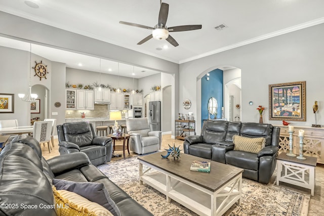 living room featuring ceiling fan with notable chandelier, visible vents, arched walkways, and ornamental molding