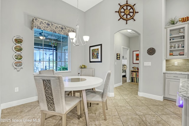 dining space featuring baseboards, arched walkways, an inviting chandelier, and light tile patterned flooring