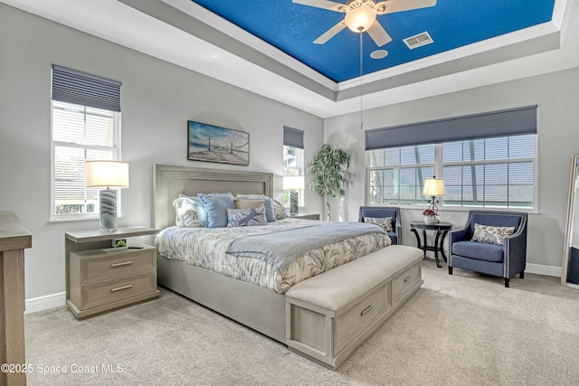 bedroom featuring baseboards, a tray ceiling, light carpet, and visible vents