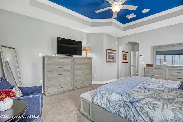 carpeted bedroom with baseboards, visible vents, a tray ceiling, arched walkways, and ornamental molding