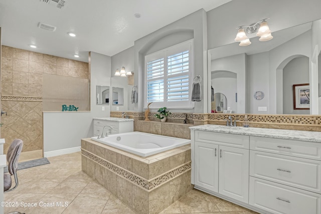 full bathroom featuring visible vents, a garden tub, vanity, and a walk in shower