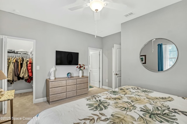 bedroom with visible vents, light carpet, a walk in closet, a closet, and baseboards