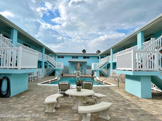 view of home's community with a pool, stairs, and a patio area