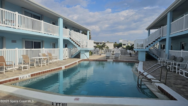 community pool with fence, stairs, and a patio area