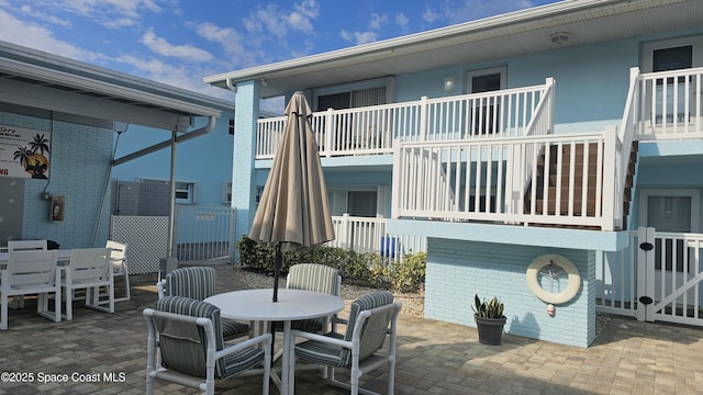 view of patio featuring outdoor dining space, stairway, and fence