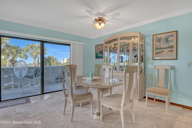 dining space featuring a textured ceiling, ornamental molding, baseboards, and ceiling fan