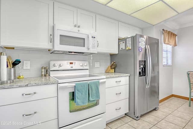 kitchen featuring decorative backsplash, white appliances, light tile patterned floors, and white cabinetry