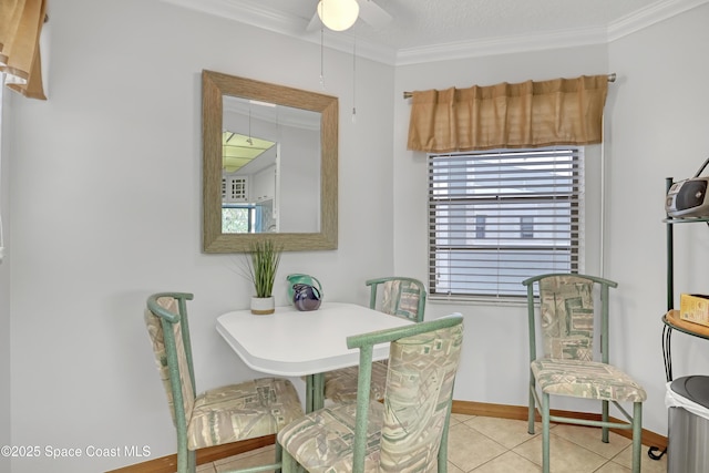 tiled dining space featuring ceiling fan, baseboards, and ornamental molding