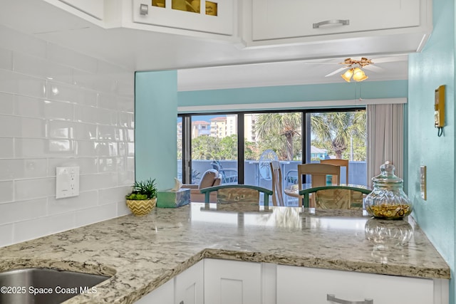 kitchen with white cabinetry, plenty of natural light, light stone countertops, and tasteful backsplash