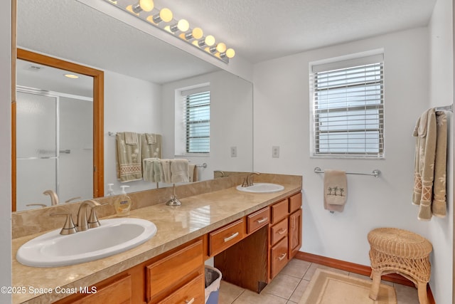 full bath with a sink, a shower stall, tile patterned floors, and double vanity