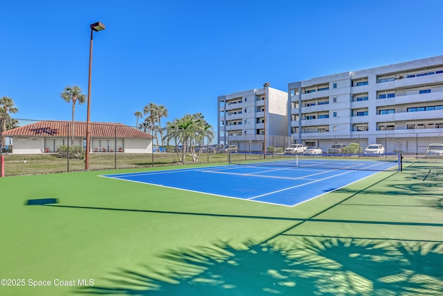 view of tennis court with community basketball court and fence