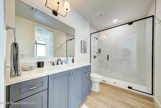 bathroom with vanity, wood finished floors, visible vents, a stall shower, and toilet