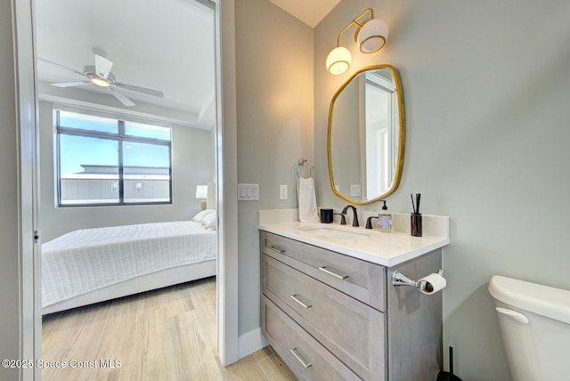 ensuite bathroom featuring vanity, a ceiling fan, wood finished floors, ensuite bathroom, and toilet