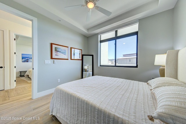 bedroom featuring a tray ceiling, parquet floors, baseboards, and ceiling fan