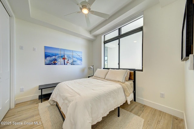 bedroom featuring light wood-style flooring, a ceiling fan, and baseboards