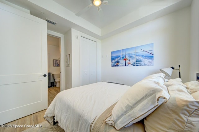 bedroom with light wood finished floors, visible vents, a ceiling fan, and a closet