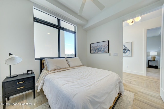 bedroom with a ceiling fan, light wood-style floors, and baseboards