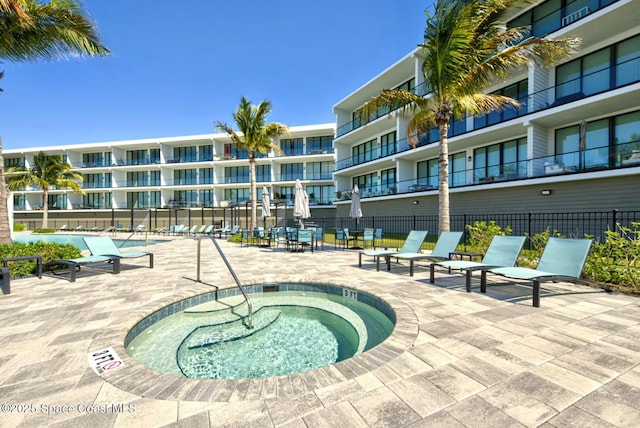 view of swimming pool featuring a patio area, fence, and a hot tub