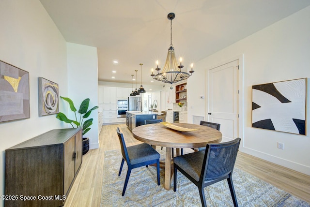 dining space featuring light wood finished floors, baseboards, beverage cooler, recessed lighting, and an inviting chandelier