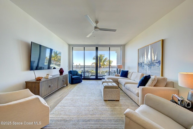 living area featuring floor to ceiling windows, light wood-type flooring, and ceiling fan