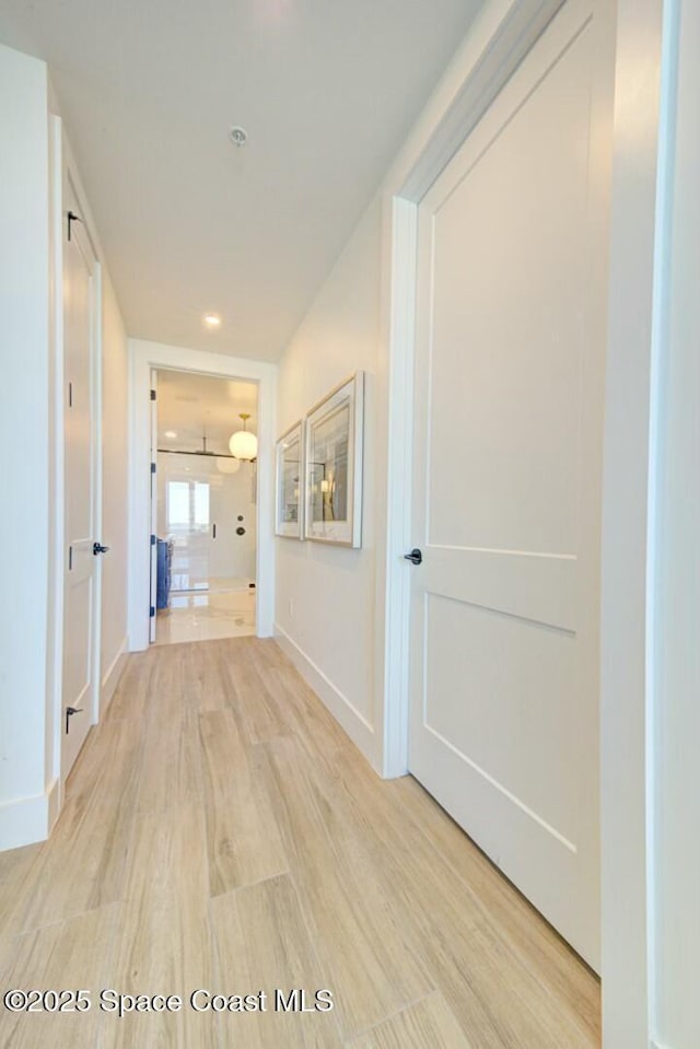 corridor featuring baseboards and light wood-style floors