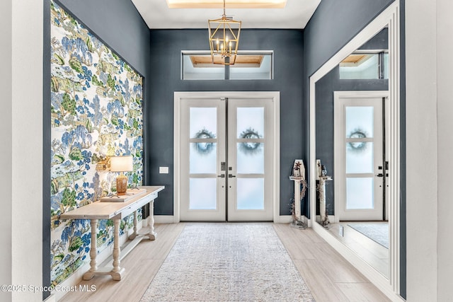 foyer featuring a wealth of natural light, a notable chandelier, french doors, and wood finish floors