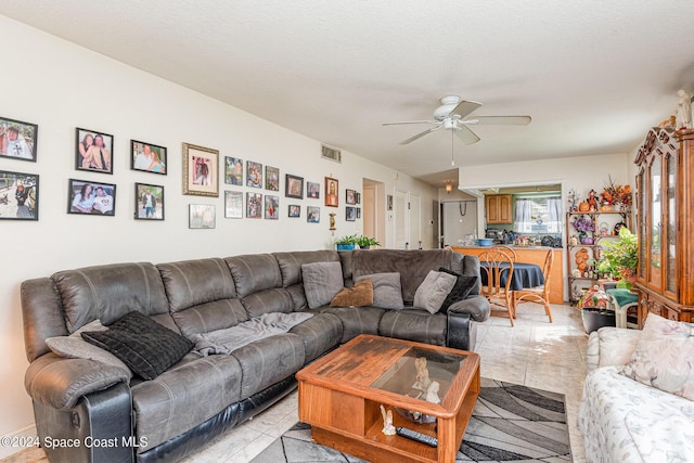 living area featuring visible vents, a textured ceiling, and ceiling fan